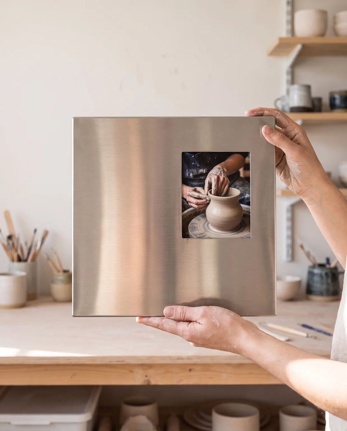 Ferrani Mono Frame held in a pottery studio, with a photograph of hands shaping a clay vase.